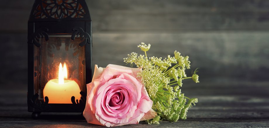 Memorial candle and flowers on wooden background